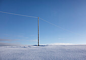 Hölzerner Strommast auf leerer, schneebedeckter Landschaft, Elektroindustrie, Stromleitung