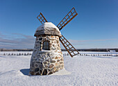 Old stone windmill on snowy landscape at winter.
