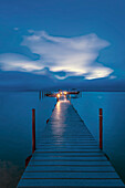 Jetty Dock am Ozean im Morgengrauen mit dramatischem Himmel darüber, USA