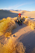 Woman sitting in the sand in Death Valley at sunrise, USA