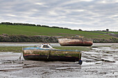 Two boats beached at low tide,with muddy hulls and frayed mooring lines