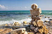 A cairn, pile of stones on the beach at the water's edge
