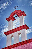 Architektonisches Detail, rote und weiße Farbe und Eisernes Kreuz auf dem Dach einer Kirche in Cancun, Halbinsel Yucatán, Mexiko