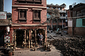 Frau in Souvenir Shop neben von Erdbeben zerstörtem Haus, Bhaktapur, Lalitpur, Kathmandu Tal, Nepal, Himalaya, Asien, UNESCO Weltkulturerbe
