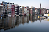 Typische Amsterdam-Häuser mit Reflexionen im Damrak-Kanal, Amsterdam, Noord-Holland, Niederlande
