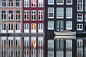 Typische Amsterdam-Häuser mit Reflexionen im Damrak-Kanal, Amsterdam, Noord-Holland, Niederlande