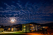 Stadt Caslano mit Mondlicht und Wolken bei Nacht im Tessin, Schweiz.