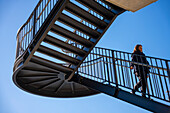 Woman Walking Down on a Staircase Against Blue Clear Sky with Sunlight in Lugano, Ticino, Switzerland.