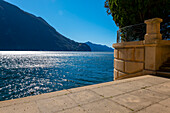 Treppe am Wasser mit Blick auf die Berge über den Luganersee an einem sonnigen Tag in Lugano, Tessin, Schweiz.