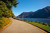 Walkway on the Waterfront with Mountain View over Lake Lugano in a Sunny Day in Lugano, Ticino, Switzerland.