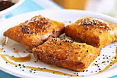 Feta im knusprigen Teigmalntel mit schwarzem Sesam und Honig, serviert in der Taverne To Steki Tou Manoli auf der Platea von Paleokastro auf der Insel Samos in Griechenland