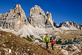 Man and woman hiking with Drei Zinnen in the background, on Monte Campedelle, Drei Zinnen, Dolomites, UNESCO World Natural Heritage Dolomites, Veneto, Veneto, Italy
