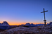 Gipfelkreuz des Strudelkopf mit Blick auf Drei Zinnen und Cristallogruppe in der Morgendämmerung, Strudelkopf, Dolomiten, UNESCO Weltnaturerbe Dolomiten, Südtirol, Italien
