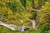 Three people looking at autumnal Allerheiligen waterfalls, Allerheiligen, Black Forest National Park, Black Forest, Baden-Württemberg, Germany