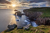 Die untergehende Sonne am Land's End in Cornwall, aufgenommen mit einer langen Verschlusszeit an einem Abend Mitte Mai, als das Sonnenlicht durch den natürlichen Seebogen von Enys Dodman schien.