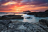 Der Leuchtturm von Godrevy wurde kurz vor Sonnenuntergang von Felsen unterhalb von Godrevy Point an der Nordküste von Cornwall aufgenommen.