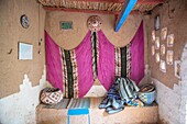 Interior of sitting nook with hung colorful fabric in traditional mud-brick built house,Tighmert Oasis,Morocco.