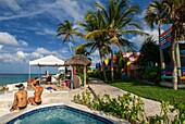 Touristen am Pool und Spa des Hotel Compass Point Resort am Love Beach Nassau, Bahamas, Karibik. Bunte Cottages im Compass Point Beach Club.