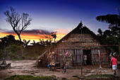 Die Sonne geht über strohgedeckten Hütten im Dorf Tijuca unter, nahe Manaus, Amazonas, Brasilien, Südamerika (Montage)