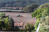 Ländliche Landschaft mit Traktor auf gepflügtem Feld
