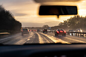 Verkehr auf der Autobahn bei Sonnenuntergang vom Auto aus gesehen