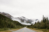Kanada, Yukon, Whitehorse, leere Straße, die hügelige Landschaft im Nebel überquert