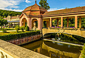 Bridge over the Sinn in the spa gardens of Bad Brueckenau with a view of the colonnade and the Parkhotel, Rhoen, Bavaria, Germany