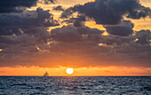 USA, Florida, Boca Raton, Sonnenaufgang über dem Meer mit Silhouette des Segelboots in der Ferne