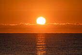 Flammender Sonnenaufgang im orangefarbenen Himmel über dem Ozean