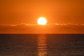 Blazing sunrise in orange sky over ocean