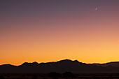 USA, New Mexico, Santa Fe, Crescent moon above Jemez Mountains at sunset