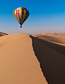 Dubai, United Arab Emirates, Colorful hot air balloon flying over sand dunes