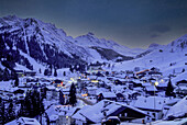 Italien, Dolomiten, Alta Badia, Dorf mit Schnee im Bergtal in der Abenddämmerung bedeckt