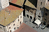 Italien, Toskana, San Gimignano, Blick aus der Vogelperspektive auf alte Stadtgebäude und Platz mit Straßencafé