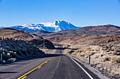 USA, California, Bishop, Highway 6 crossing desert landscape with snowcapped Sierra Nevada Mountains in distance