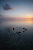 Blick auf einen Steinkreis im Wasser am Ammersee bei Sonnenuntergang, Ammersee, Bayern, Deutschland, Europa