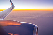 Blick auf Flugzeugmotor und Wolken über dem Meer bei Sonnenuntergang, Atlantik, Europa