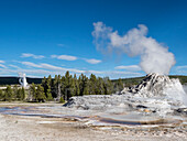 Castle Geyser steaming, with Old Faithful erupting behind, in Yellowstone National Park, UNESCO World Heritage Site, Wyoming, United States of America, North America