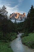 Fluss im grünen Tal mit Cristallo und Popena-Gruppe im Hintergrund bei Sonnenuntergang, Dolomiten, Südtirol, Italien, Europa