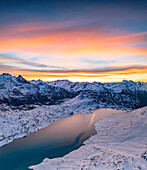 Luftaufnahme des zugefrorenen Sees Lago Bianco am Berninapass bei Sonnenaufgang mit Schnee bedeckt, Engadin, Graubünden, Schweiz, Europa
