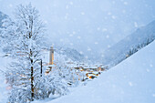 Schneeflocken fallen auf Berghütten im märchenhaften Alpendorf zur Weihnachtszeit, Valgerola, Veltlin, Lombardei, Italien, Europa