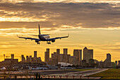 Aircraft landing at London City Airport at sunset, with Canary Wharf and O2 Arena in background, London, England, United Kingdom, Europe