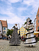 Stadtfest mit Stelzenläufern in der Reichenstraße mit Blick auf das Kloster St. Mang in Füssen im Ostallgäu in Bayern in Deutschland