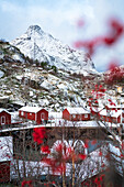 Rote Rorbu-Hütten, eingerahmt von schneebedeckten Bergen im Winter, Nusfjord, Nordland County, Lofoten-Inseln, Norwegen, Skandinavien, Europa