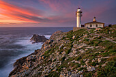 Sea landscape view of Cape Tourinan Lighthouse at sunset with pink clouds, Galicia, Spain, Europe