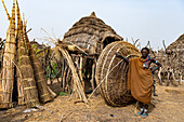 Woman in front of her hut with ready prepared reeds, Jiye tribe, Eastern Equatoria State, South Sudan, Africa