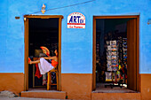 Eine Frau mit Ventilator entspannt sich in einer Tür, Trinidad, Sancti Spiritus, Kuba, Westindien, Mittelamerika