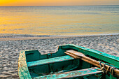 Caribbean, Grenada, Grenadines. Sunset and wooden fishing boat on Grand Anse Beach