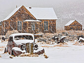 USA, Kalifornien, Bodie. Verlassenes Auto und Gebäude im Schneefall