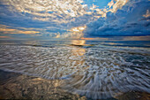 USA, Georgia, Tybee Island. Clouds and waves in morning light at the beach.